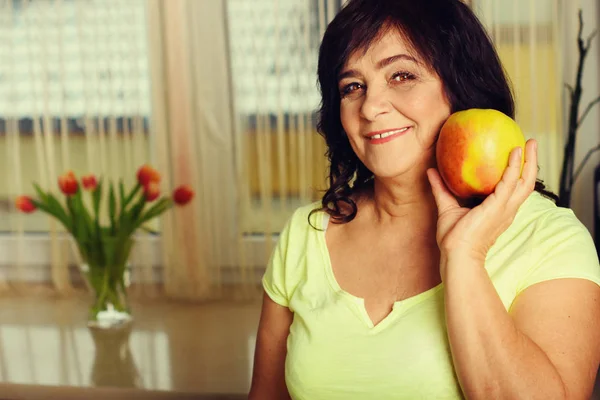 Portrait of happy mature woman with apple — Stock Photo, Image