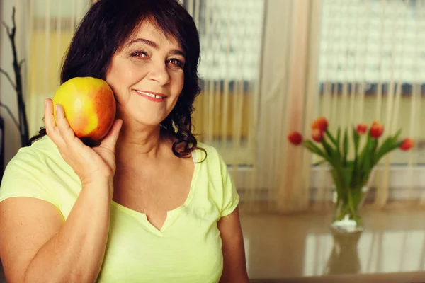 Portrait of happy mature woman with apple — Stock Photo, Image