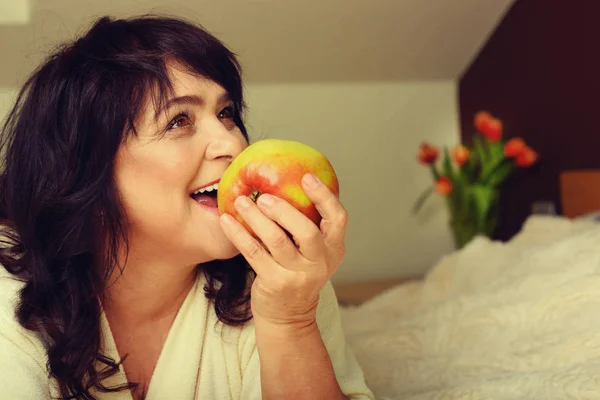 Portrait of happy mature woman with apple — Stock Photo, Image