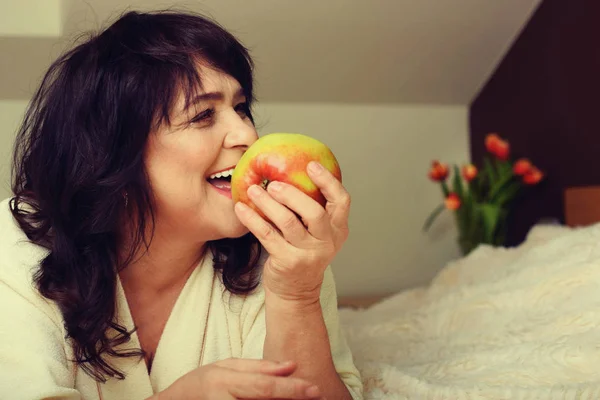 Portrait of happy mature woman with apple — Stock Photo, Image