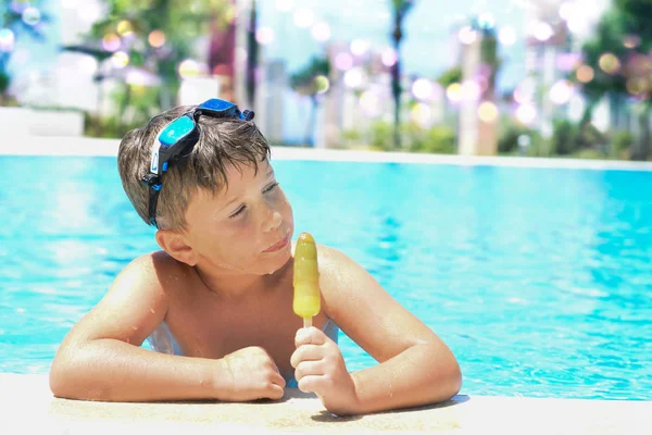 Mignon petit garçon avec crème glacée à côté de la piscine — Photo