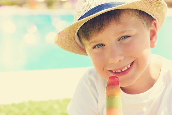 Mignon petit garçon avec crème glacée à côté de la piscine — Photo