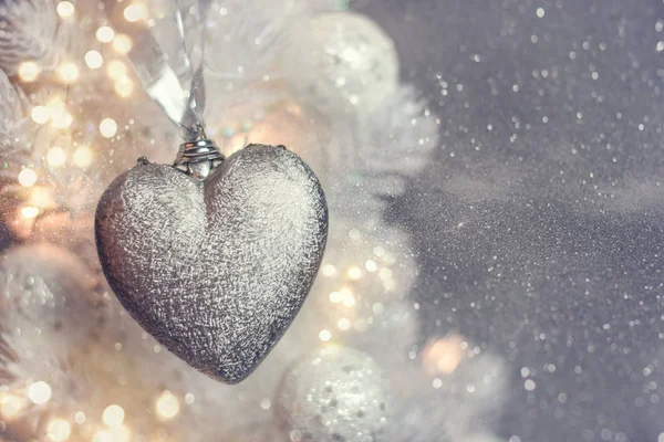Closeup of heart shaped bauble hanging from a decorated Christmas tree. — Stock Photo, Image
