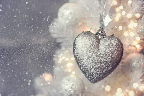 Closeup of heart shaped bauble hanging from a decorated Christmas tree. — Stock Photo, Image