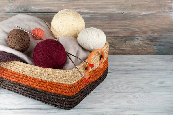 Bola de lã, agulhas e suéter de lã com raios para tricô artesanal em cesta na mesa de madeira . — Fotografia de Stock