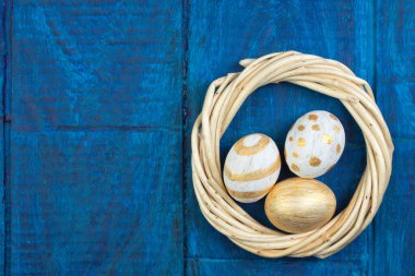 Mutlu Paskalyalar. Tahta masa arkasında izole edilmiş yumurtalar... Toplar, sarmaşıklardan örülmüş çelenkler. Uzayı metin için kopyala. Üst görünüm.