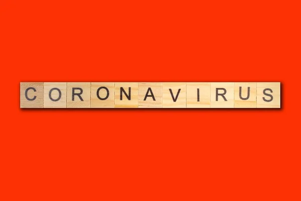 Palabra de Coronavirus escrita en bloque de madera sobre fondo rojo. vista superior . —  Fotos de Stock