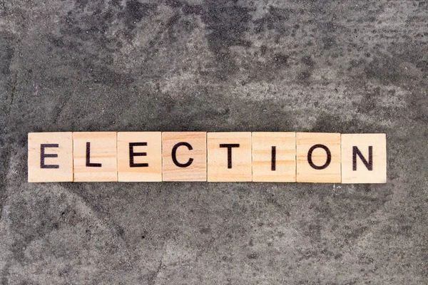 Palabra electoral escrita en bloque de madera, sobre fondo de hormigón gris. Vista superior . — Foto de Stock