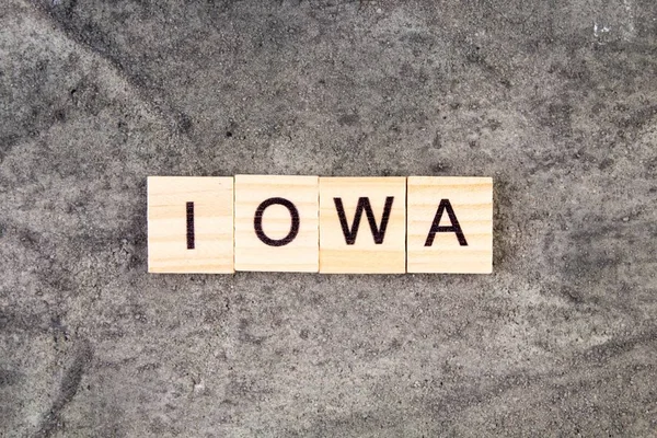 Iowa woord geschreven op houten blok, op grijze betonnen achtergrond. Bovenaanzicht. — Stockfoto