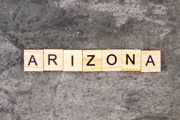 Arizona woord geschreven op houten blok, op grijze betonnen achtergrond. Bovenaanzicht. — Stockfoto