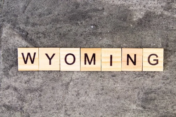 Wyoming woord geschreven op houten blok, op grijze betonnen achtergrond. Bovenaanzicht. — Stockfoto