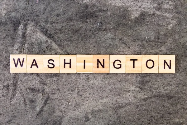 Washington słowo napisane na bloku drewna, na szarym tle betonu. Widok z góry. — Zdjęcie stockowe