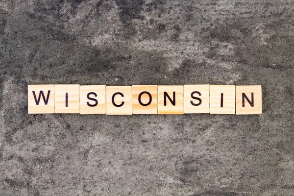 Wisconsin woord geschreven op houten blok, op grijze betonnen achtergrond. Bovenaanzicht. — Stockfoto