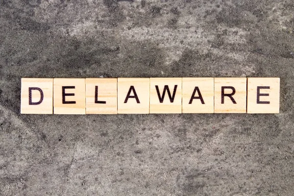 Delaware kelimesi tahta blokta, gri beton arka planda yazılı. Üst görünüm. — Stok fotoğraf