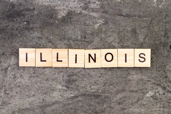 Illinois woord geschreven op houten blok, op grijze betonnen achtergrond. Bovenaanzicht. — Stockfoto