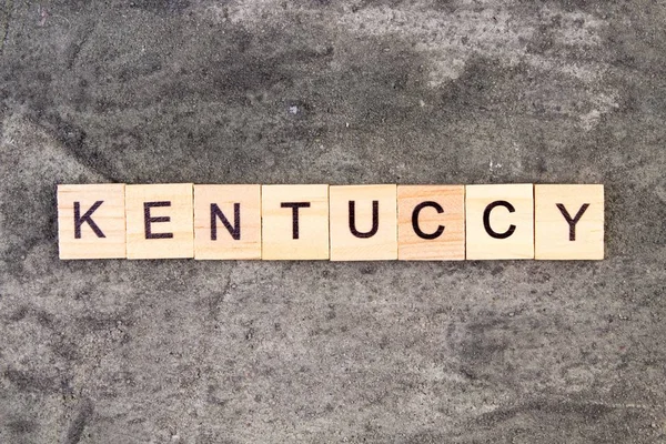 Kentucky ord skrivet på träblock, på grå betong bakgrund. Ovanifrån. — Stockfoto