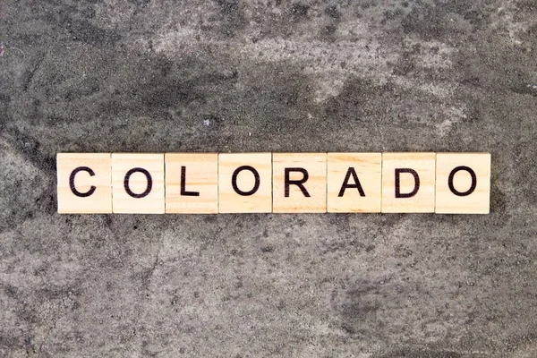 Colorado woord geschreven op houten blok, op grijze betonnen achtergrond. Bovenaanzicht. — Stockfoto