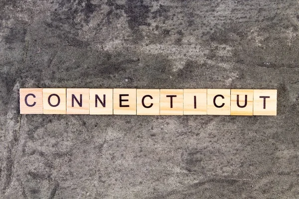 Connecticut słowo napisane na bloku drewna, na szarym tle betonu. Widok z góry. — Zdjęcie stockowe