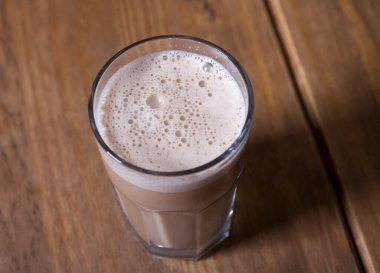 Ahşap bir masada bir bardak kapuçino.