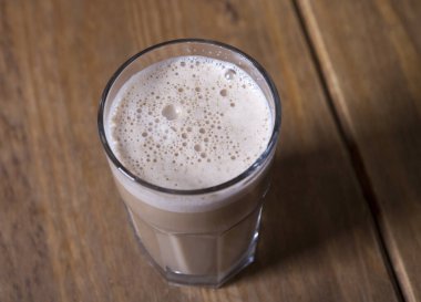 Ahşap bir masada bir bardak kapuçino.