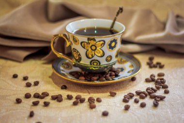 Kahve natürmort, güçlü kahve kokusu. Bir fincan kahve ve kahve taneleri nazik bir arka plan üzerinde