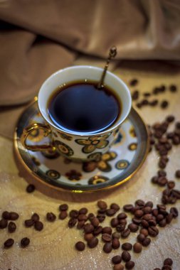 Kahve natürmort, güçlü kahve kokusu. Bir fincan kahve ve kahve taneleri nazik bir arka plan üzerinde