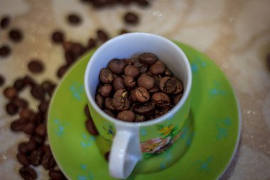 Kahve natürmort, güçlü kahve kokusu. Bir fincan kahve ve kahve taneleri nazik bir arka plan üzerinde