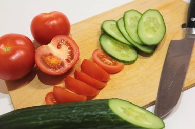 Bir kesme tahtası üzerinde dilimlenmiş salatalık ve domates