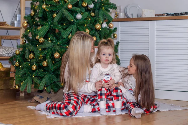 Mutter und Tochter am Weihnachtsbaum. Weihnachtszeit. Schwestern. Frohe Weihnachten und frohe Feiertage fröhliche Mutter und ihre süßen Töchter tauschen Geschenke. — Stockfoto