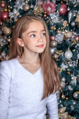 Noel ağacının yanındaki küçük tatlı kız. Yeni yıl ve Noel. Noel ağacı süslemesi.