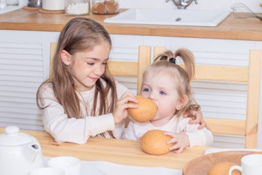 Mutfakta ekmek yiyen iki kız kardeş. 