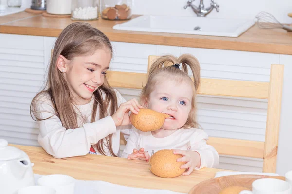 Mutfakta ekmek yiyen iki kız kardeş. 