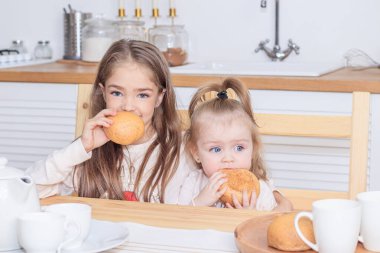 Mutfakta ekmek yiyen iki kız kardeş. 