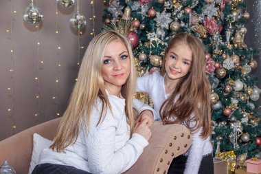 Anne ve kızı Noel ağacının yanında poz veriyor.