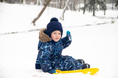 Küçük çocuk kışın parkta yürüyüşe çıktı. Kış Parkı. Kış tulumlu bir çocuk. Parkta kar .