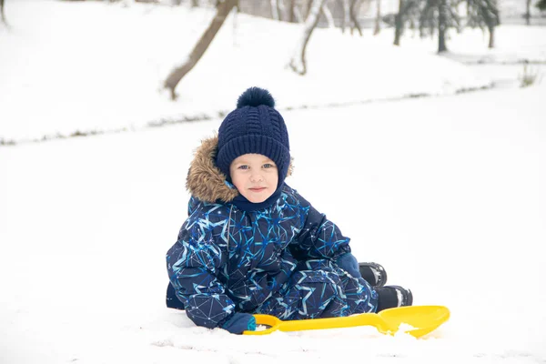 Little boy on a walk in the Park in winter. Winter park. A boy in winter overalls. Snow in the Park . — Stock Photo, Image