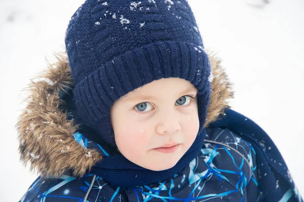 Petit garçon en promenade dans le parc en hiver. Parc d'hiver. Un garçon en salopette d'hiver. Neige dans le parc  . — Photo