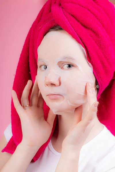 Fabric white mask on the face of a young girl . Female beauty. Skin care. Healthy skin. Youth and beauty. Article about face masks. Face mask. Article about skin care . White mask . The girl in the ma — Stock Photo, Image