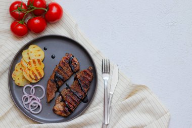 Domatesli domuz bifteği. Gri arka planda ev yemeği kavramında domuz eti. Restoranın menü tasarımı. Makale et hakkında.
