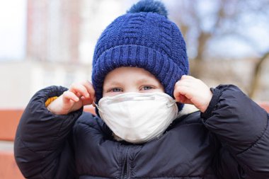 Çocuk parkında maskeli bir çocuk. Sağlığa. Coronavirus. Çocuğun yüzünde tıbbi maske var. - Güvenlik. Zatürree ve grip. Solunum koruması. Eğlenceler
