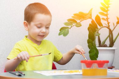 Çocuk boyalarla resim çiziyor. Evinde otur. Uzaktan eğitim. Çocuklar için eğitim dersleri. Çocukların boş vakitleri hakkında bir makale. Evde çocuk dersleri. Resimler