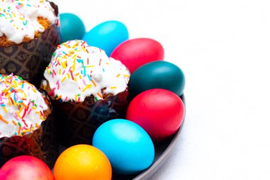 Renkli boyalı yumurta ve beyaz arka planda bir tabakta Paskalya pastası. Paskalya. Dini bayram. Metin için yer.