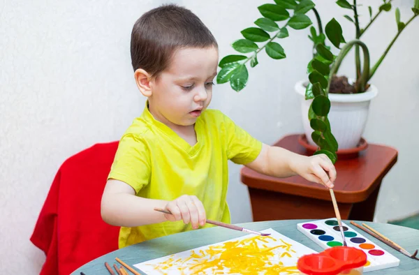 The boy draws with paints . Sit at home. The remote training. Educational classes for children. Article about children's leisure. Home children's classes. Paints