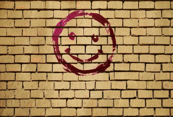 Smile emoticon on the background of the Brick wall. Drawn smiley smile symbol. Joyful sign.