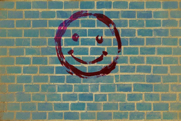 Smile emoticon on the background of the Brick wall. Drawn smiley smile symbol. Joyful sign.