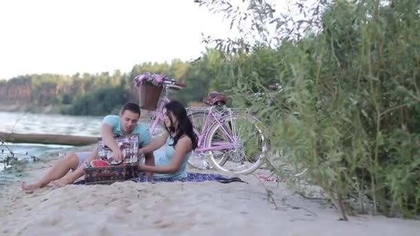 Ett ungt par omfamnar på stranden av floden — Stockvideo