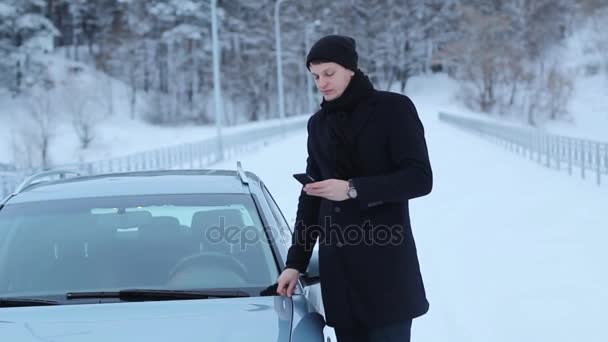 Snygg kille nära bilen med telefonen — Stockvideo