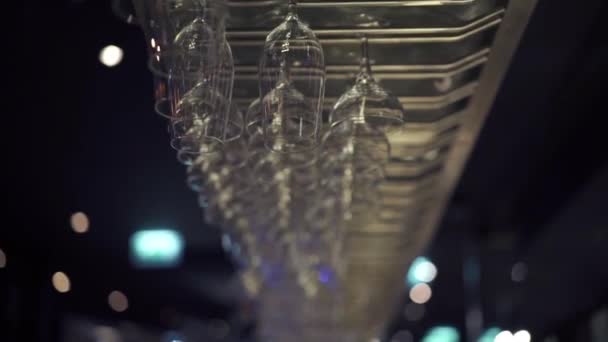 Group of empty wine glasses hanging from metal beams in a bar — Stock Video