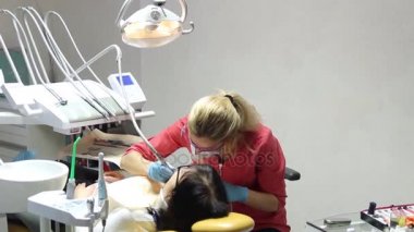 Kadın dişçi hastalarının dişlerinde çalışıyor.