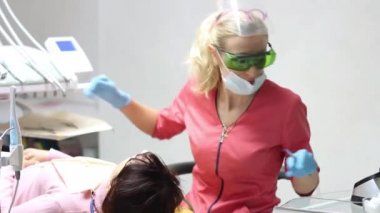 Kadın dişçi hastalarının dişlerinde çalışıyor.